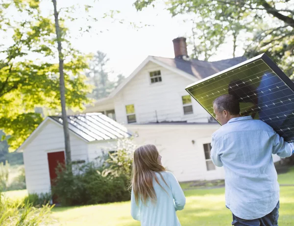 Man und Tochter laufen mit Photovoltaik Modul zum Haus
